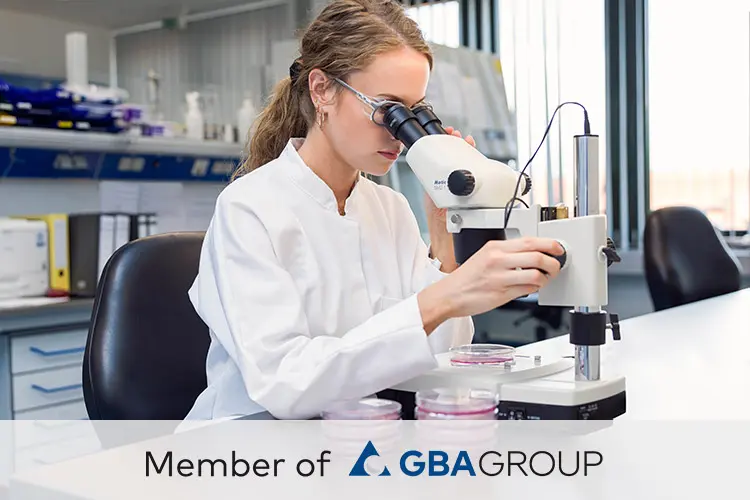 Bild einer wissenschaftlichen Mitarbeiterin bei der Arbeit am Mikroskop in einem Labor der GBA Group.